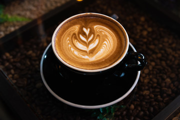Latte art coffee in black cup on  table, Dark tone