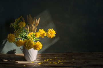 yeliow flowers in white jug on dark background