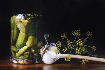 pickled cucumbers in a glass jar with garlic and dill on a dark background.  inverted jar with...