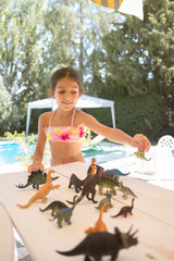 Obraz na płótnie Canvas toy dinosaur on table, six year old girl picking