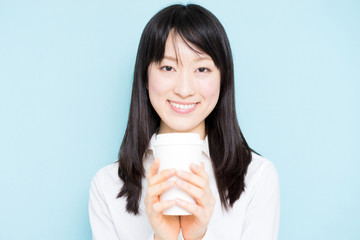 Young business woman drinking coffee against light blue background