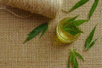 Green hemp leaves and oil on sackcloth background