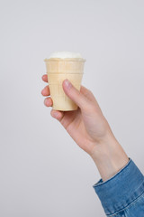 Vertical cropped close up photo of hand showing demonstrating waffle cup with ice cream isolated grey background
