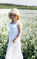 Close up portrait of little cheerful girl in flower summer field. Childhood, nature concept