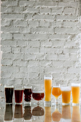 Glasses of dark and light beer and ale in sunlight on brick wall background. Cold delicious alcohol...