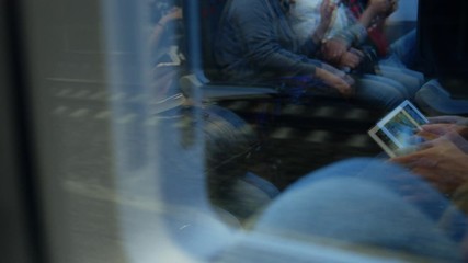 Reflection of rush hour commuters bored on train