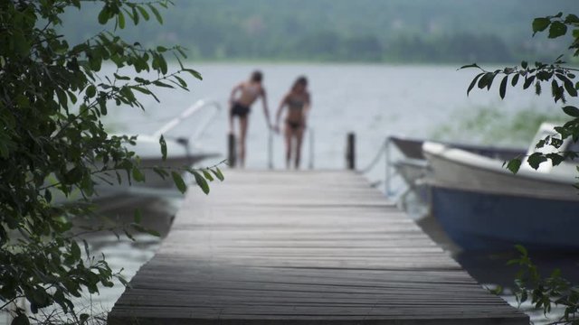 Medium, kids jumping off a deck into a lake in Sweden