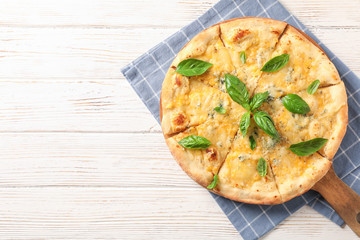 Towel, board, cheese pizza with basil on wooden background, copy space