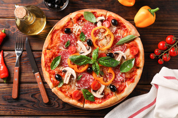 Delicious pizza and ingredients on wooden background, top view
