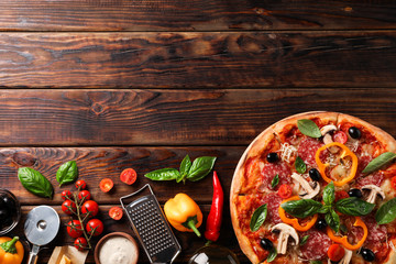 Delicious pizza and ingredients on wooden background, copy space