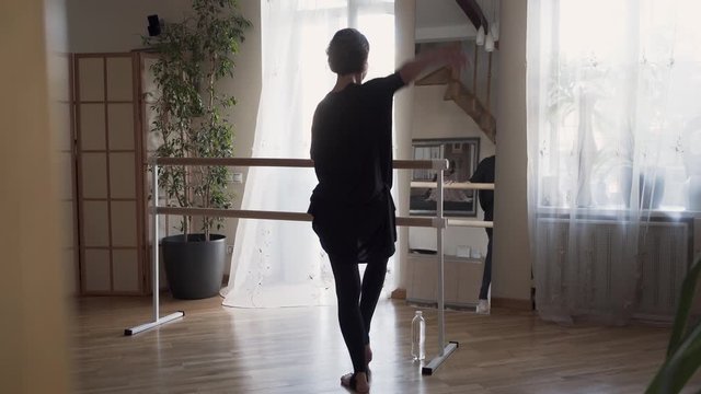 Confident attractive flexible mature ballerina with great body dancing at home in front of the mirror. Elegant slim woman in black clothes doing exercises indoors. Happy life, keeping in shape