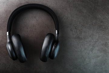 Fototapeta na wymiar Black bluetooth headphones on a dark background with blue and orange backlight. In-Ear Headphones for DJs