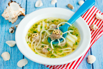 Octopus soup for kids lunch - potato soup with meatballs and spaghetti shaped funny octopuses in white bowl