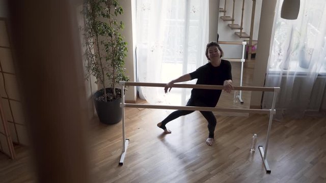 Pretty flexible mature woman practicing at home. Elegant slim woman in black clothes doing exercises indoors. Happy life, keeping in shape.