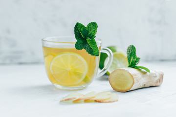 Green tea with ginger,mint and lime on the white wooden table 