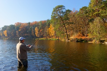 Fototapeta na wymiar angler catching the fish at sunny autumnal day
