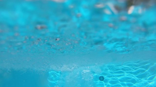 Young man running on diving board and doing a gainer and viewing him under water.