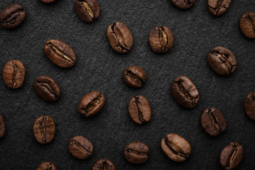 whole coffee beans on black stone background. top view