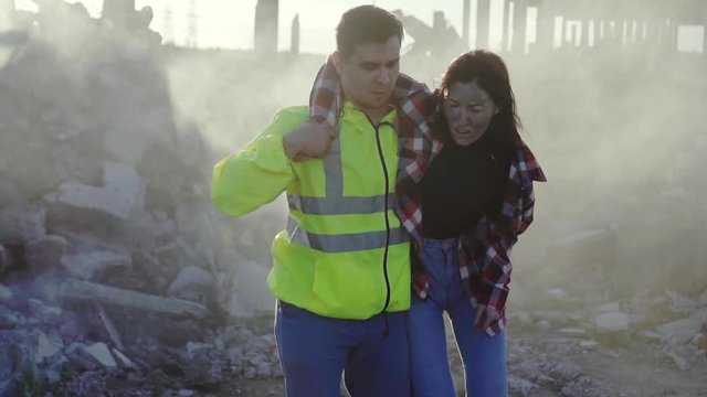 a man from the rescue service in uniform helps the victim of an earthquake or fire