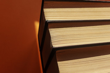 Black-bound books with yellowed pages on an orange background. Contrast light. The concept of libraries, reading, second-hand books, book business. Place for text, minimalism.