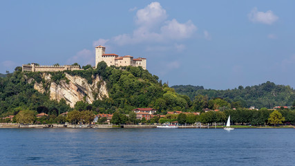 Fototapeta na wymiar A white sailboat sails on Lake Maggiore near the Rocca di Angera, Varese, Italy