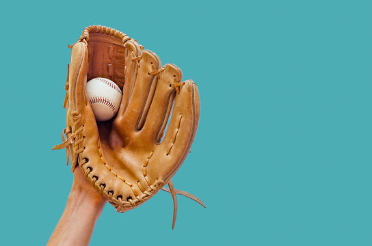 Hand in a leather baseball glove caught a ball on a green background