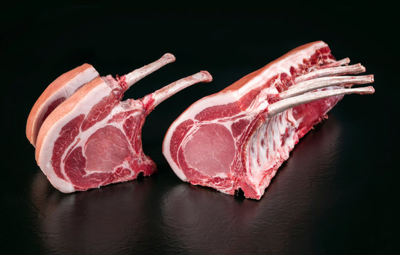 Rohes dry aged Tomahawk Steack vom Schwein am St&uuml;ck angeboten als closeup vor schwarzen Hintergrund mit Textfreiraum
