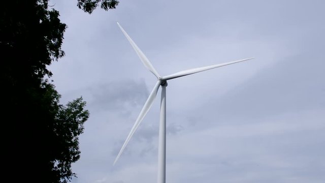 Wind turbine spins around for generating energy with clouds