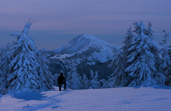 Man is enjoying view of winter mountain in twilight