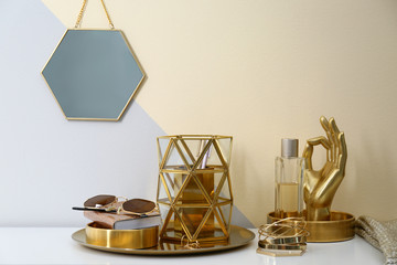 Composition with golden accessories on dressing table near color wall. Space for text