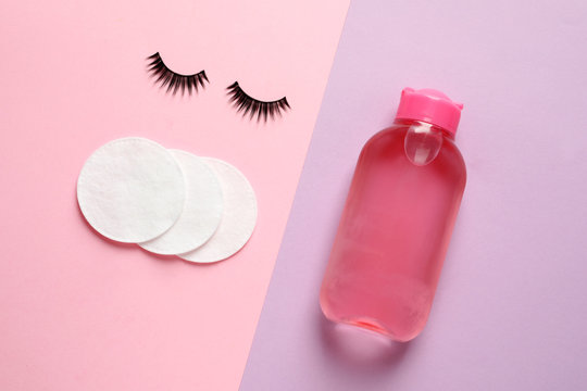 False eyelashes, cotton pads and makeup remover on color background, flat lay