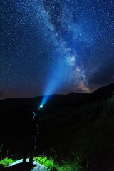 Fantastic starry night with galaxy Milky Way with a tourist and a tent on the mountain range in the Ukrainian Carpathians