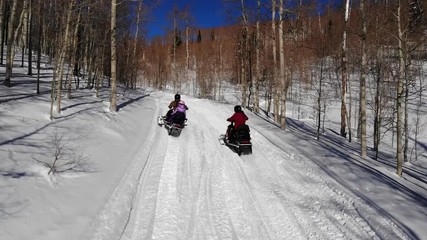 Aerial shot following snowmobilers up mountain pass