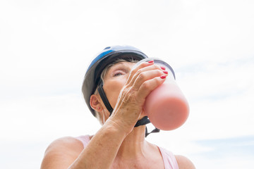 older woman with blue helmet taking sports supplementation