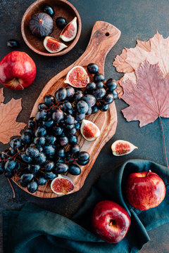 Top view of Autumn food flat lay with season fruits llike Bangalore blue grape, red apples and figs on a table.