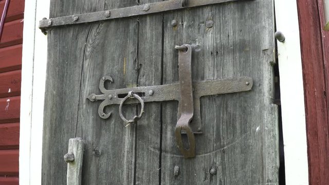 Close-up of an old wooden window shutter with an iron hasp lock