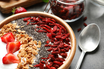 Smoothie bowl with goji berries and spoon on grey table, closeup