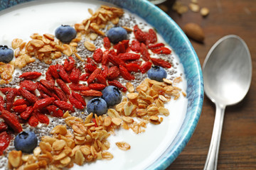Smoothie bowl with goji berries and spoon on wooden table, closeup