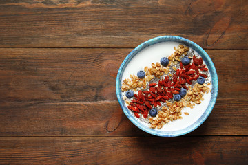 Smoothie bowl with goji berries on wooden table, top view. Space for text
