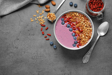 Flat lay composition of smoothie bowl with goji berries on grey table. Space for text