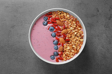 Smoothie bowl with goji berries on grey table, top view