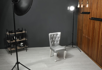 Stylish silver chair and professional equipment in photographer's studio