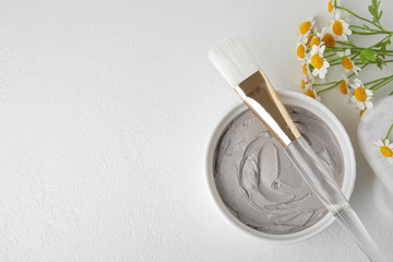 Professional face mask with flowers on white table, flat lay. Space for text