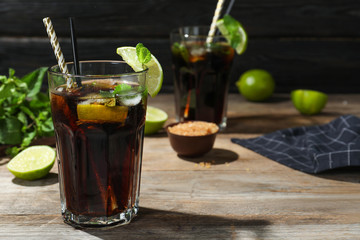 Glass of delicious cocktail with ice on table against dark wooden background. Space for text