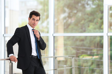 Handsome young man in stylish suit indoors. Space for text