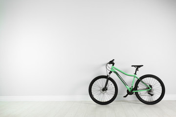 Fototapeta na wymiar Modern bicycle near white wall indoors. Space for text