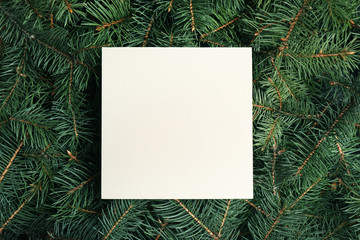 Fototapeta na wymiar Blank card on Christmas tree branches as background, top view. Space for text