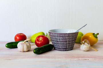 bell pepper, garlic, bowl, cucumbers and tomatoes on wooden background