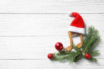 Flat lay composition with note on white wooden background, space for text. Christmas music concept