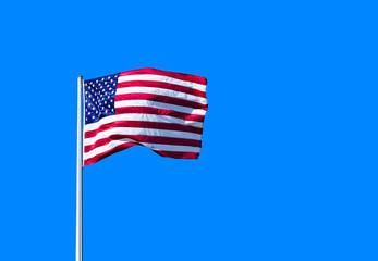 Fototapeta premium American flag waving proudly on a clear windy day, blue sky background